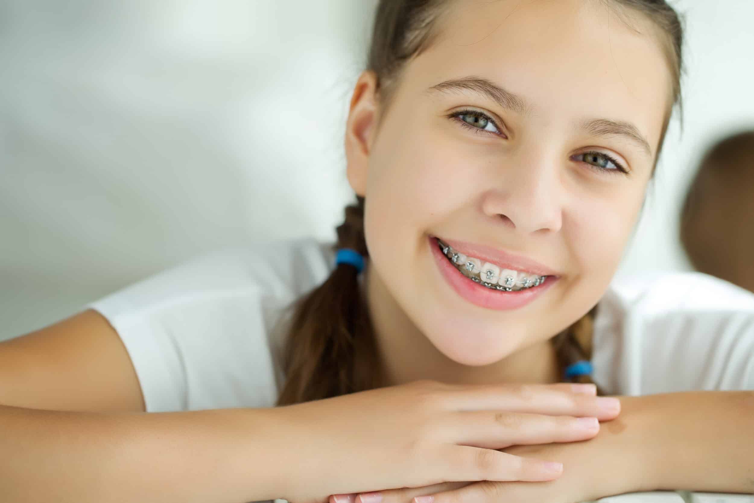 Teenage girl with braces smiles warmly at the camera.